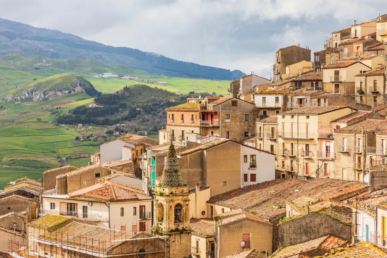 Gangi, cosa vedere: un borgo siciliano arroccato su una collina, con case in pietra e tetti rossi, circondato da verdi paesaggi montani.