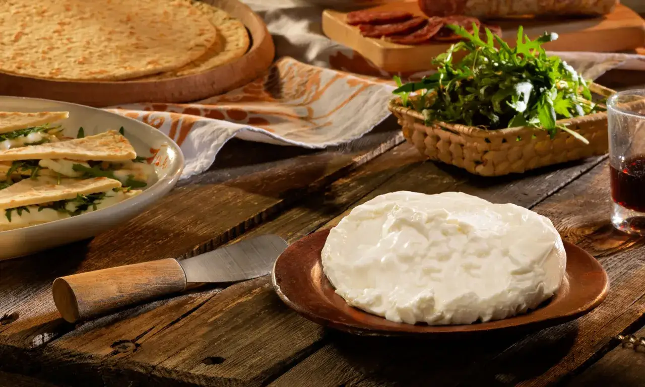 Un assaggio di cucina romagnola: piadina, squacquerone fresco, rucola e salumi su un tavolo rustico.