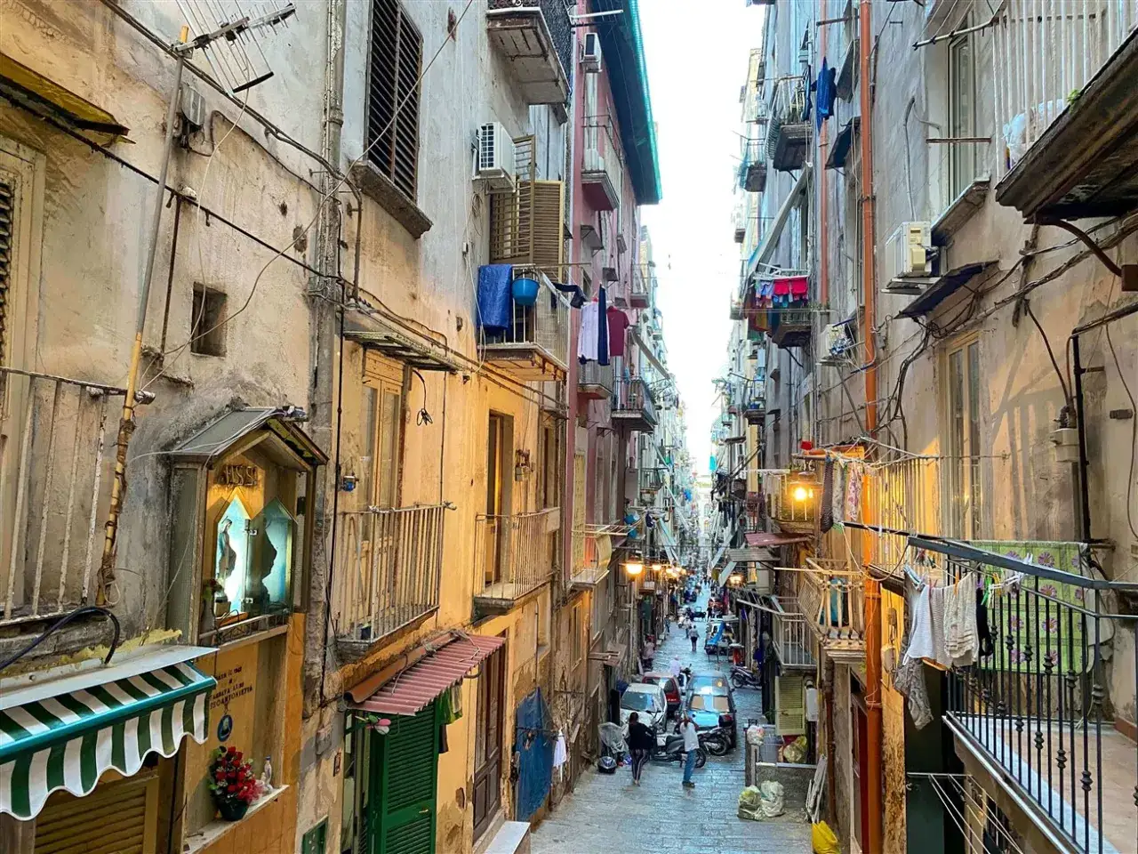 Un vicolo stretto e pittoresco a Napoli, con panni stesi e un edicola sacra. Perfetto per scoprire cosa fare a Napoli in un giorno.