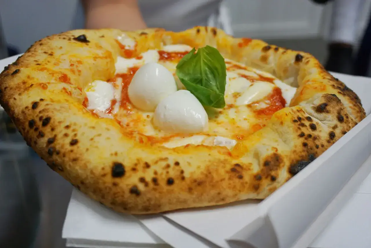 Pizza Margherita appena sfornata, con mozzarella di bufala, pomodoro e basilico. Un vero assaggio di cibo napoletano.