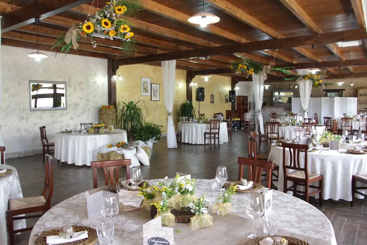 Interno della Masseria Cardillo a Presenzano, con tavoli apparecchiati per un evento, decorazioni floreali e balle di fieno.