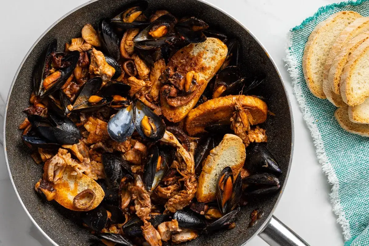 Cosa mangiare in Toscana? Un saporito guazzetto di mare con cozze, polpo e crostini, perfetto per assaporare i gusti della costa.