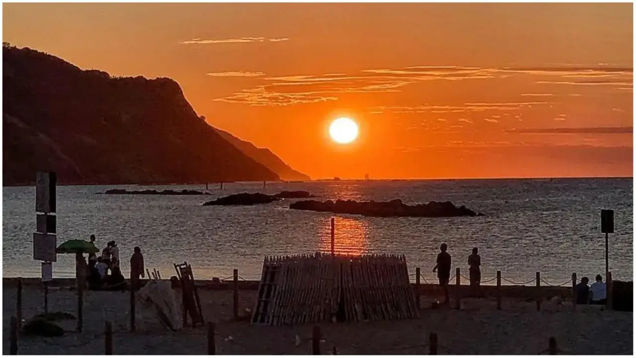 Tramonto infuocato sul mare, gente sulla spiaggia. Un'ottima idea per le cose da fare a Pesaro.