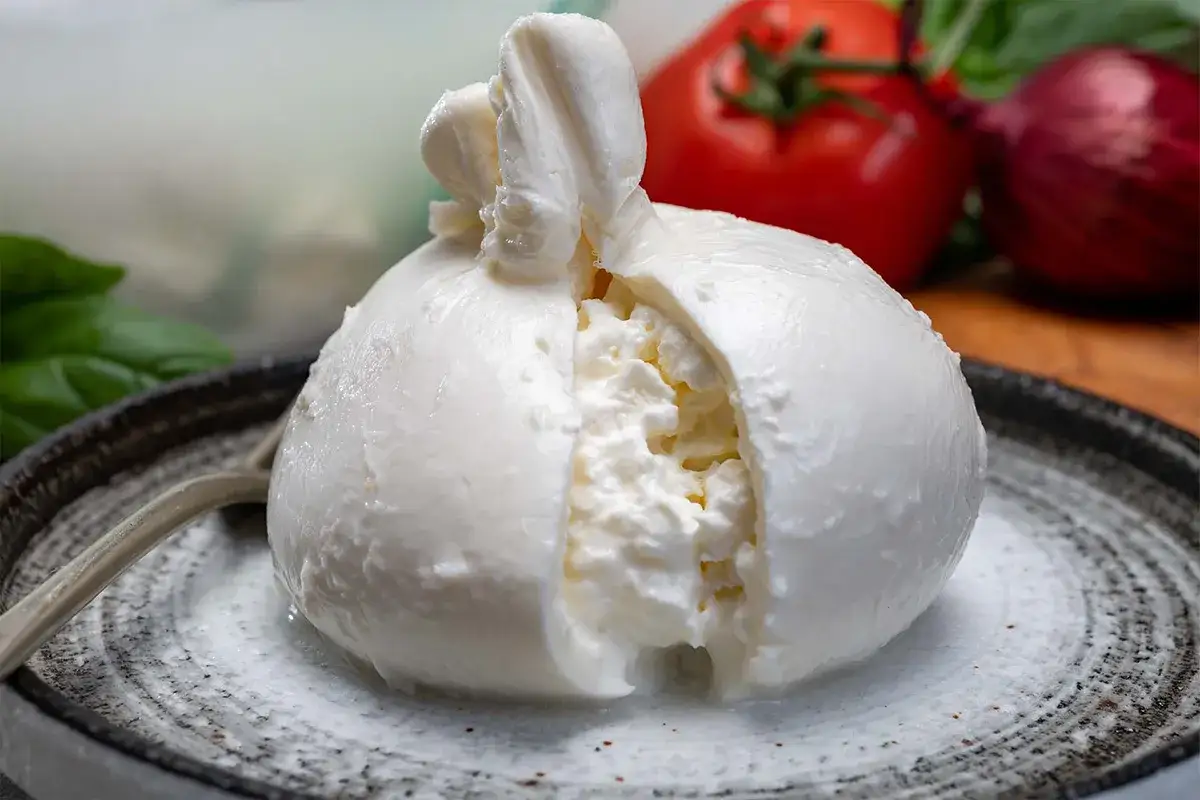 Burrata fresca, un tesoro di sapori, tra le cose tipiche pugliesi. Accompagnata da pomodoro, cipolla rossa e basilico.