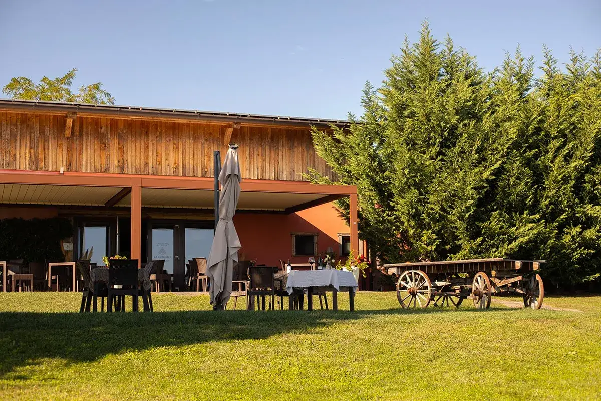 La casa rossa ai colli, con tavoli apparecchiati all'esterno e un antico carro, invita a godersi la tranquillit&agrave; della campagna.
