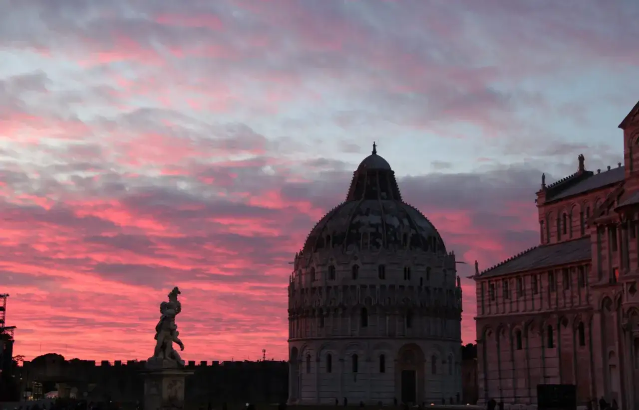 Tramonto rosa su Pisa: il Battistero e il Duomo, tra le cose da fare a Pisa, incantano sotto un cielo infuocato.