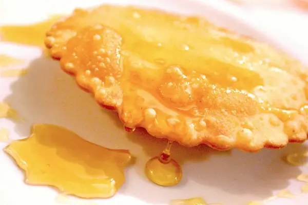 Dolce fritto, uno dei 5 piatti tipici della Sardegna, ricoperto di miele dorato.