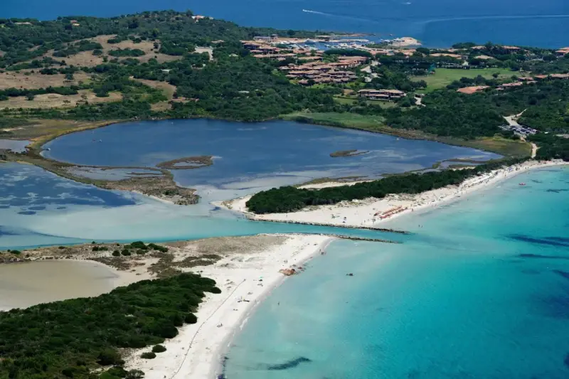Vista aerea della spiaggia La Cinta con acque turchesi, lagune interne e vegetazione lussureggiante.