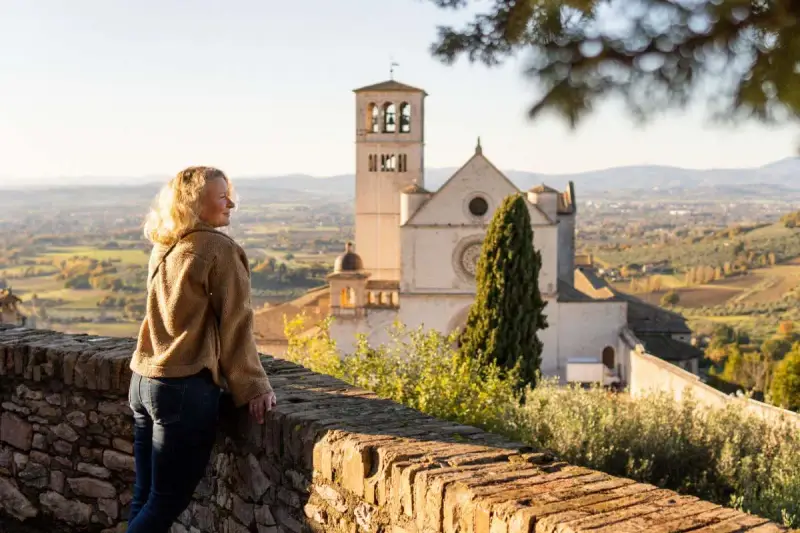 Donna ammira il panorama di Assisi, con la Basilica di San Francesco in lontananza. Un ricordo di viaggio tra Assisi e Gubbio.