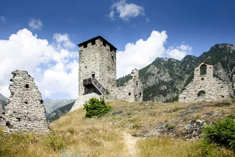 Rovine di un castello con torre in pietra, un invito a visitare la Valle d'Aosta.